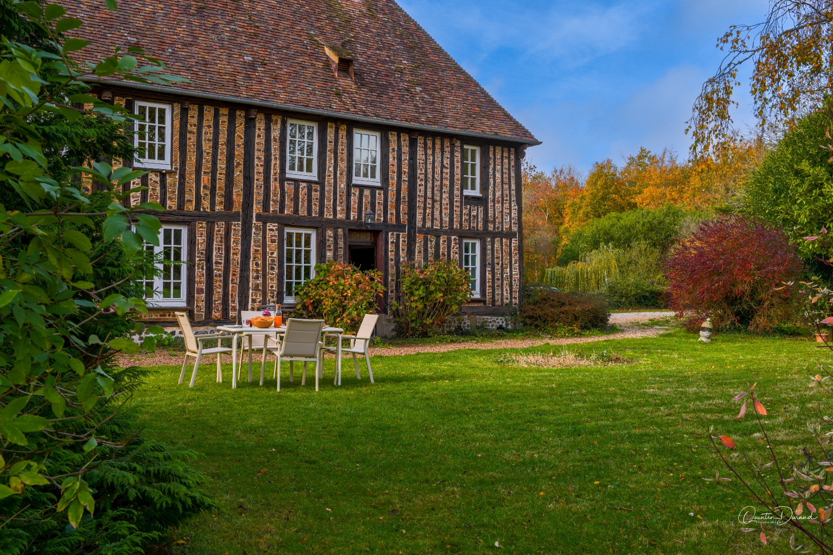 Façade à colombages du manoir avec jardin fleuri en automne
